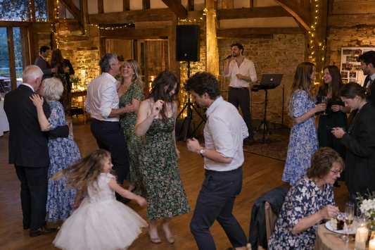 Wedding singer performing to a dancefloor of guests of all ages at a rustic wedding venue